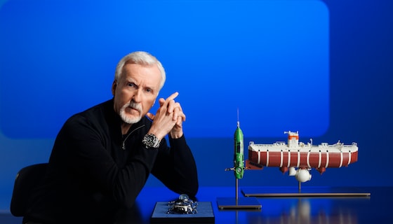 James Cameron, an Oyster Perpetual Deepsea Challenge on his wrist, posing with a model of the bathyscaphe Trieste (right), his submersible DEEPSEA CHALLENGER (centre) and (left) the two experimental watches attached to the vehicles during the dives into the Mariana Trench – respectively, the Deep Sea Special (behind) and the Rolex Deepsea Challenge (in front).