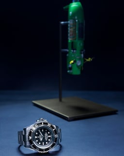 L’Oyster Perpetual Deepsea Challenge avec une maquette du submersible <i>DEEPSEA CHALLENGER</i> à l’arrière-plan