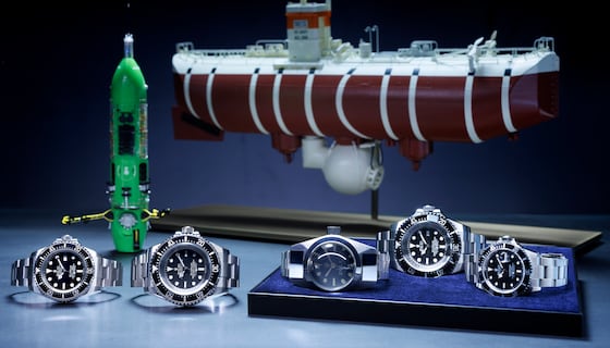 Premier plan, de gauche à droite : Oyster Perpetual Rolex Deepsea (2008), Oyster Perpetual Deepsea Challenge (2022), Deep Sea Special (1960), Rolex Deepsea Challenge (2012) et Oyster Perpetual Submariner (1986). Arrière-plan, de gauche à droite : maquettes du submersible <i>DEEPSEA CHALLENGER</i> et du bathyscaphe <i>Trieste</i>.