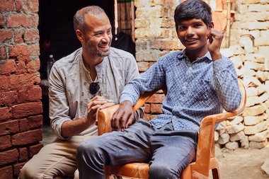 Andrew Bastawrous, CEO of Peek Vision, pictured with patient Prem Kumar in the small village of Jarmanau in northern India. Like Bastawrous, Kumar struggled at school due to vision problems. After receiving glasses through the Peek-powered programme, he was able to return to lessons.