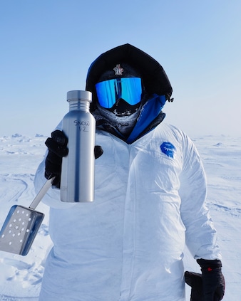 A  member of the Before It’s Gone (BIG) Arctic Research Expedition team holding up a snow sample collected in the Canadian Arctic. 