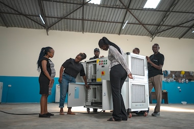 Beth Koigi (second from left) explaining the technical details of an atmospheric water generator to her team in a Majik Water warehouse. Majik Water installs these machines in arid and semi-arid regions where they extract, filter and mineralize water from the air.
