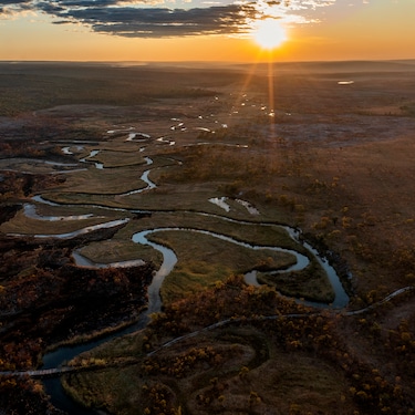 Aerial view of the sun setting over the thin and winding upper reaches of Lungwevungu River, Angola.