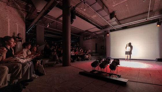 Theatre Performance, [÷] v.0.8 : Boléro, Athens Conservatoire, Athens 2023 Theatre fellow Sebastián Solórzano Rodríguez shares a live performance of his solo work [÷] v.0.8 : Boléro, specially adapted to the Installations space in Ω2 Complex. Using only light, shadow and the sound of his breath, the artist rises an invocation that surrounds the audience.