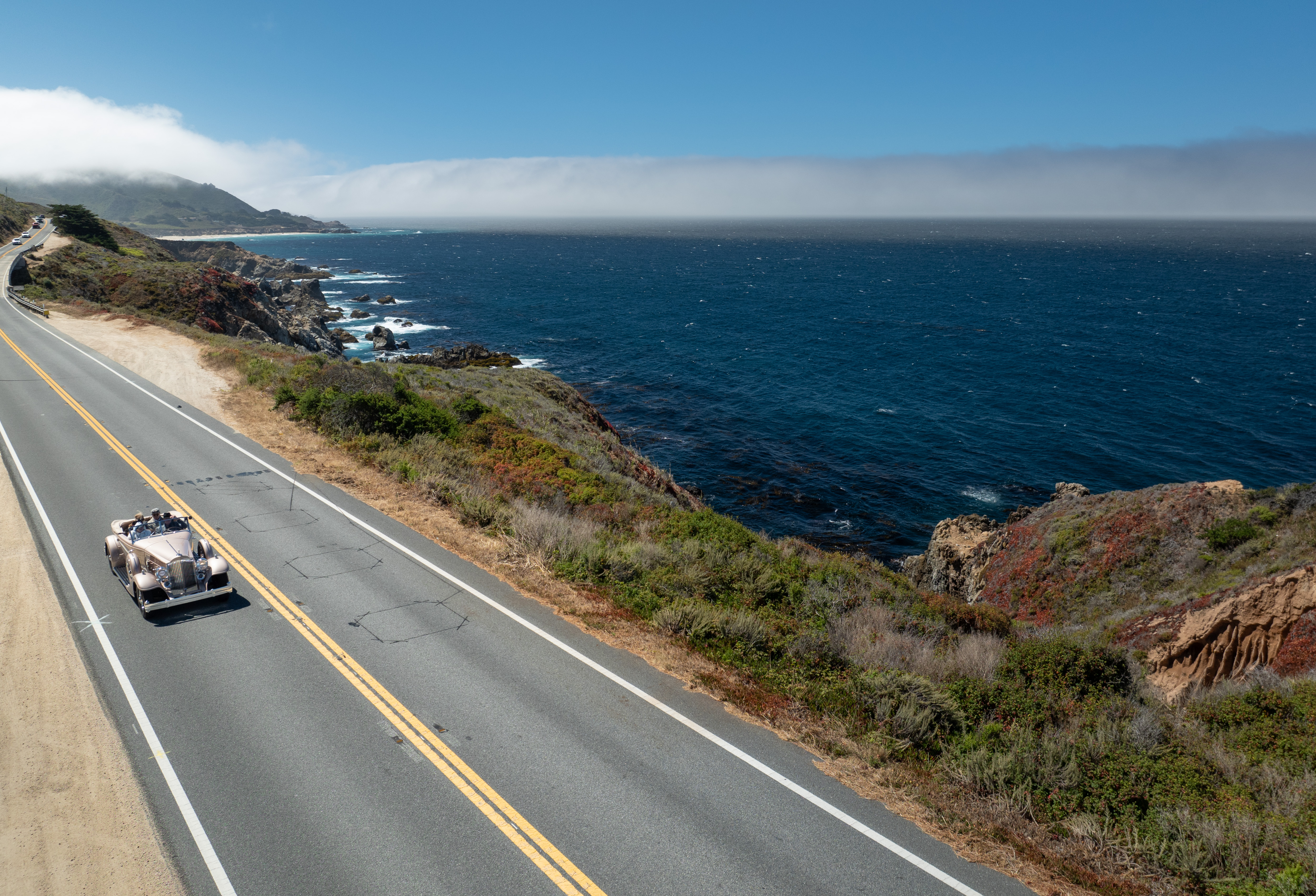 CLASSIC CAR DRIVING ALONG HIGHWAY ONE DURING THE PEBBLE BEACH TOUR D’ELEGANCE® PRESENTED BY ROLEX
